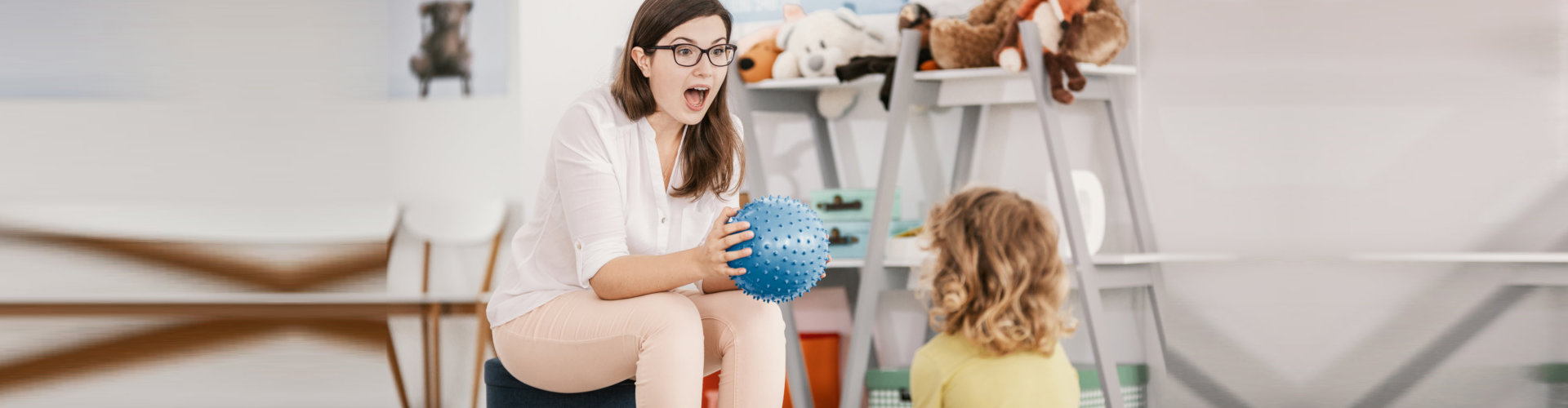 a woman playing a sensory game blue ball with a little girl
